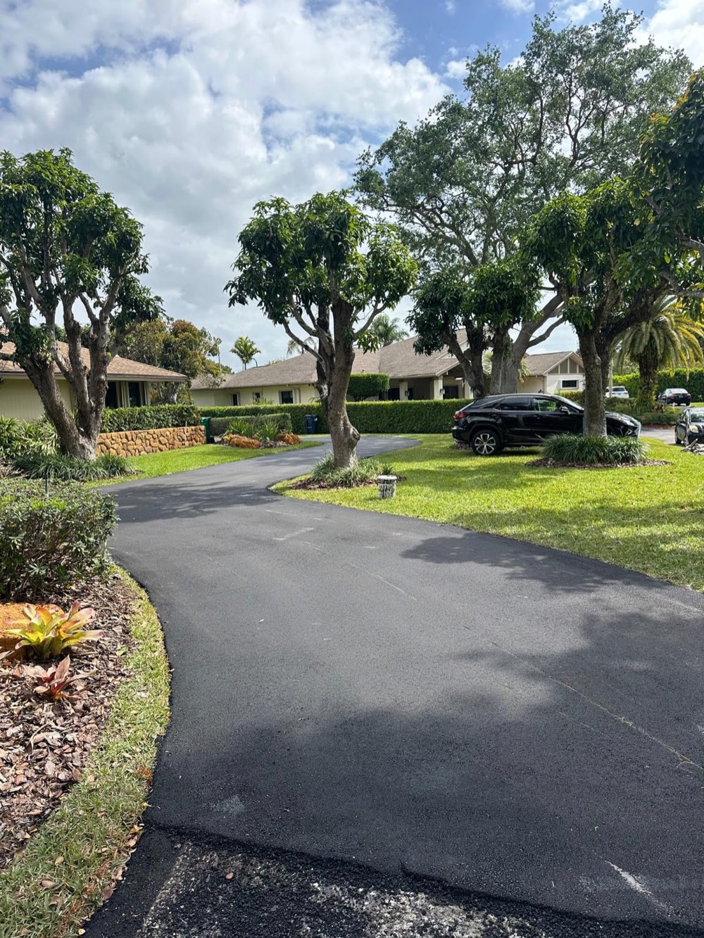 Curving asphalt driveway through a landscaped South Florida estate